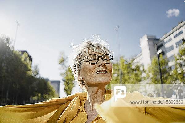 Porträt einer lächelnden reifen Frau  die das Sonnenlicht genießt