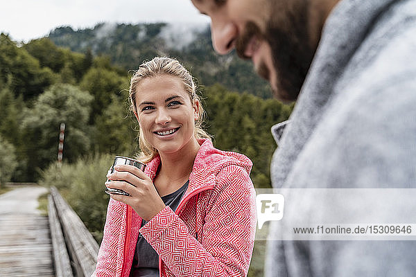 Junge Frau mit Getränk lächelt Mann während einer Wanderung an  Vorderriss  Bayern  Deutschland