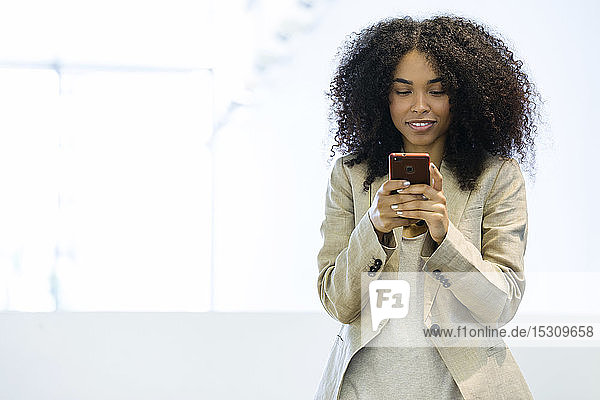 Lächelnde junge Geschäftsfrau mit einem Smartphone
