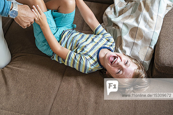 Playful father and son on couch at home