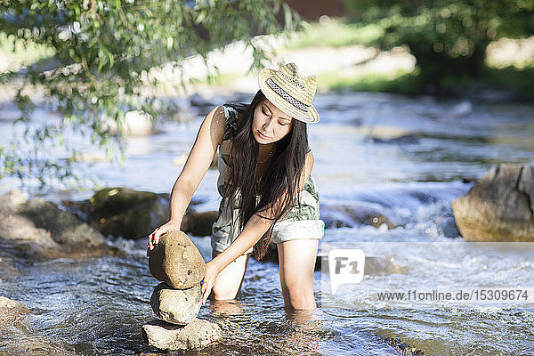 Junge Frau stapelt Steine in einem Fluss