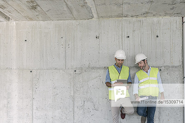 Zwei Arbeiter mit Tablette auf der Baustelle