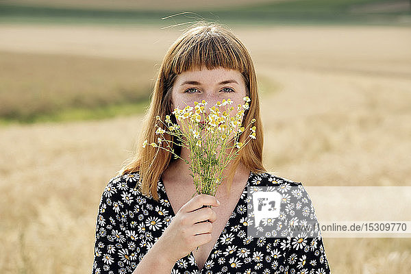 Portrait of young woman with bunch of chamomile flower