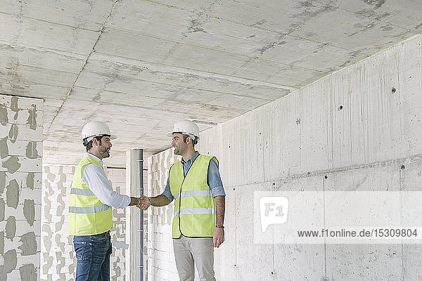Zwei Arbeiter schütteln sich die Hände auf der Baustelle