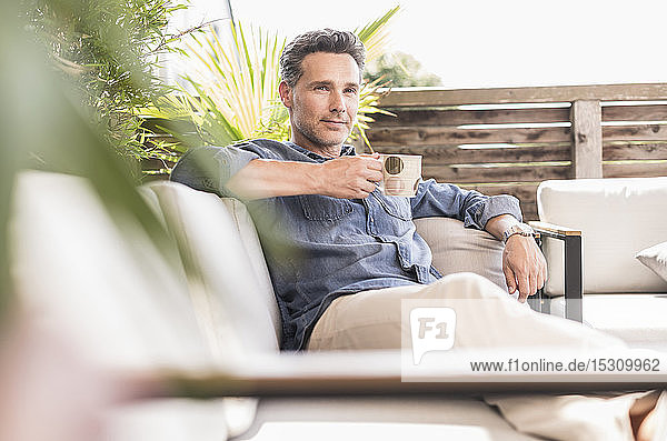Confident man relaxing on the terrace drinking coffee