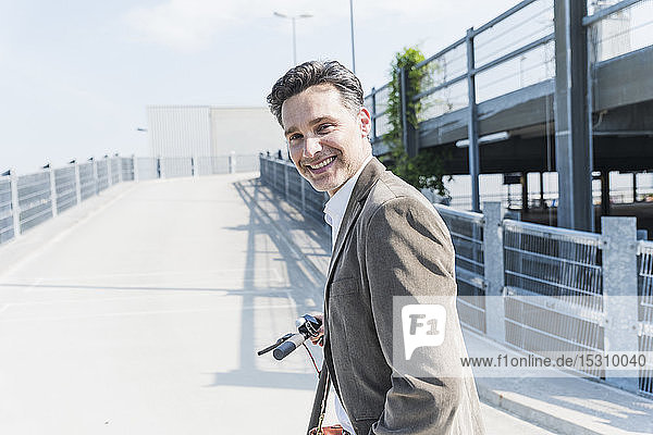 Smiling businessman with E-Scooter