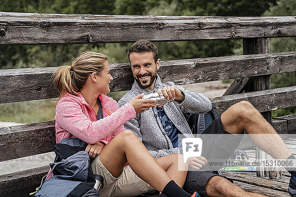 Young couple having a break on a wooden bridge during a hiking trip  Vorderriss  Bavaria  Germany