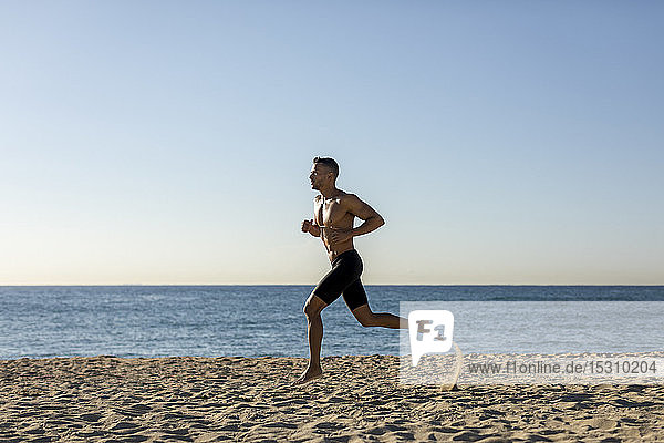 Barechested man jogging on the beach