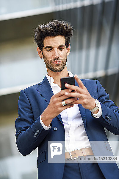 Geschäftsmann benutzt Mobiltelefon vor einem Bürogebäude