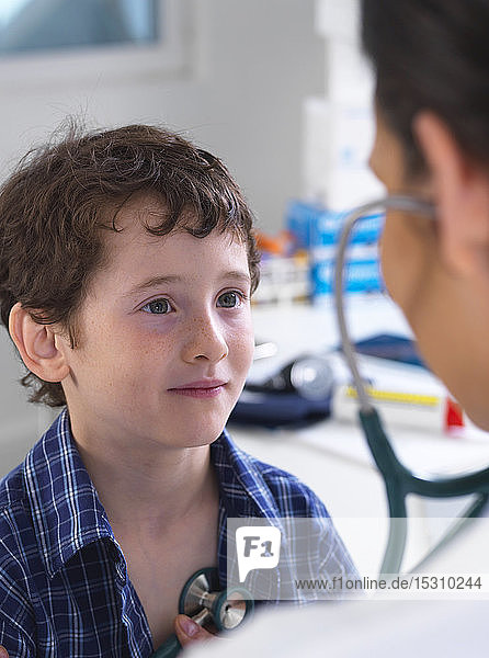 Ärztin  die einen Jungen mit einem Stethoskop untersucht