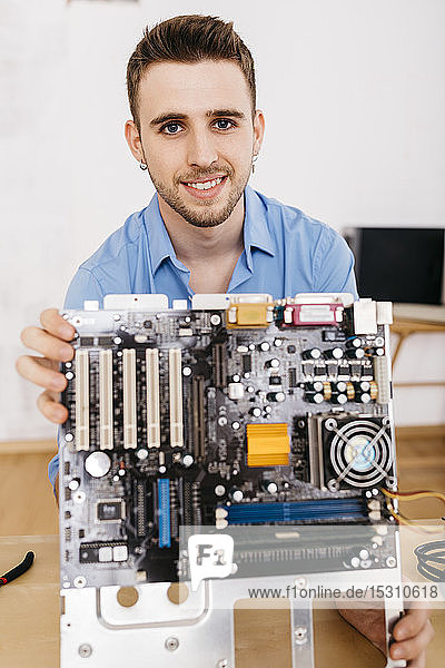 Porträt eines lächelnden Technikers  der die Hauptplatine eines Computers hält