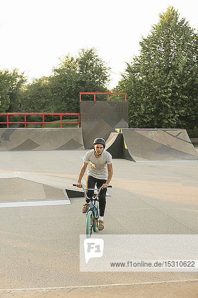 Young man riding BMX bike at skatepark