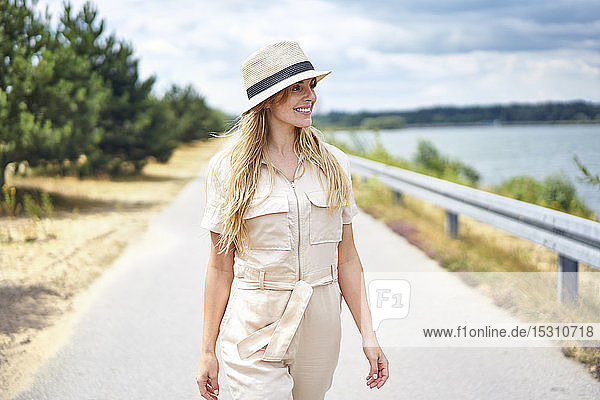 Smiling woman walking on rural road at the lakeside