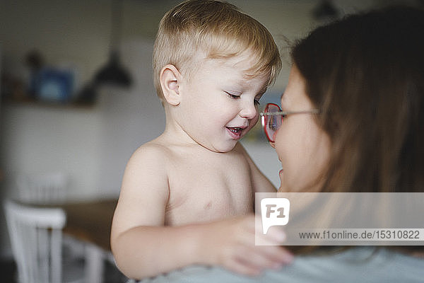 Porträt eines glücklichen kleinen Jungen auf den Armen seiner Mutter zu Hause