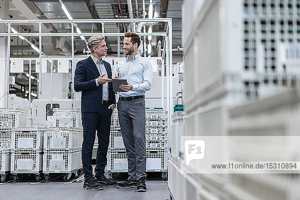 Two businessmen with tablet talking in a modern factory