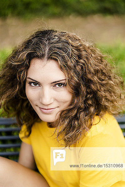 Porträt einer lächelnden jungen Frau auf einer Parkbank