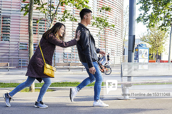 Happy woman pushing boyfriend down the street  Barcelona  Spain