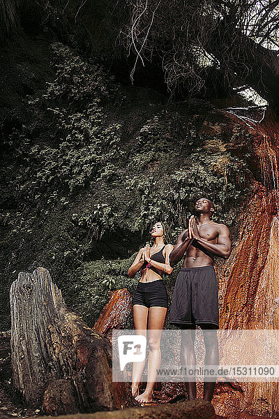 Couple practising yoga at waterfall  tree position