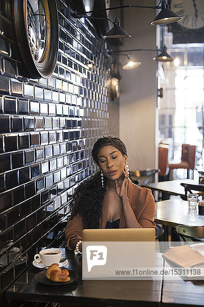 Chic businesswoman using laptop at table in a cafe