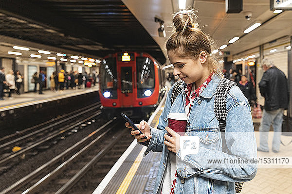 Young woman at subway station using a smartphone