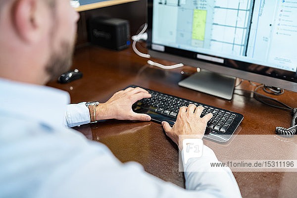Close-up of businessman working on desktop pc in office