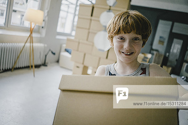Porträt eines lächelnden rothaarigen Jungen mit Pappkarton