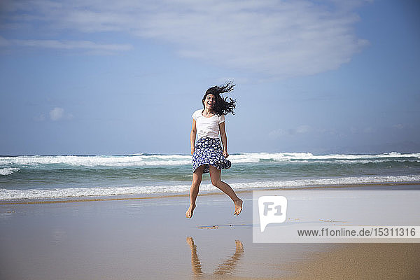 Lachende Frau springt am Strand in die Luft  Fuerteventura  Spanien