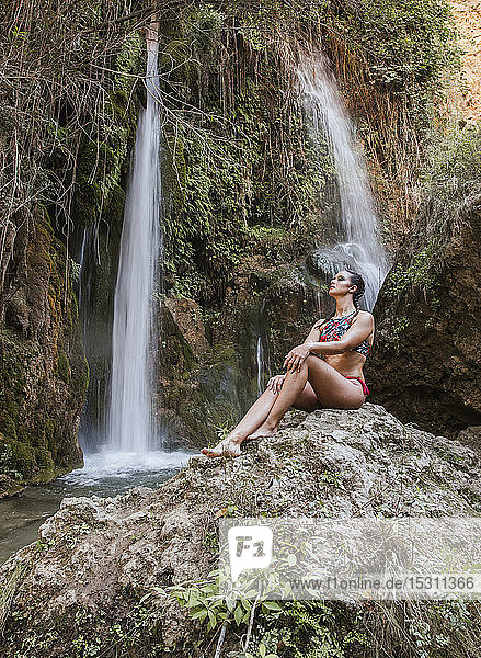 Young woman posing at a waterfall