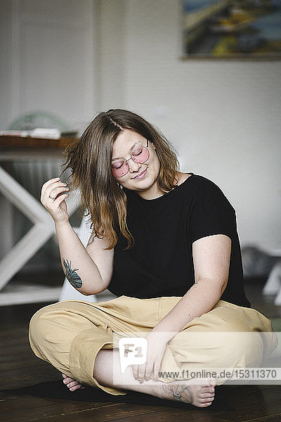 Porträt einer tätowierten Frau  die zu Hause auf dem Boden sitzt