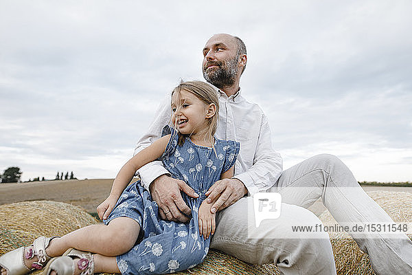 Vater und Tochter sitzen auf Heuballen