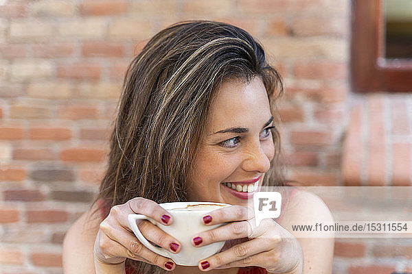 Porträt einer lachenden jungen Frau mit Tasse Kaffee
