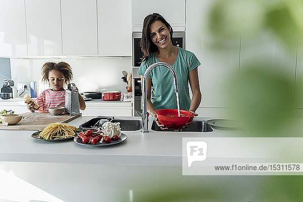 Happy mother and daughter cooking in kitchen together