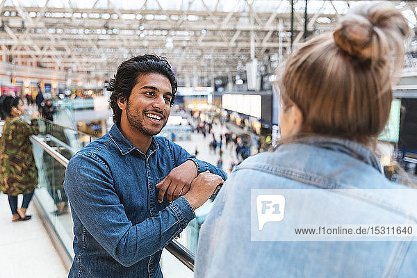 Porträt eines jungen Mannes im Gespräch mit seiner Freundin am Bahnhof
