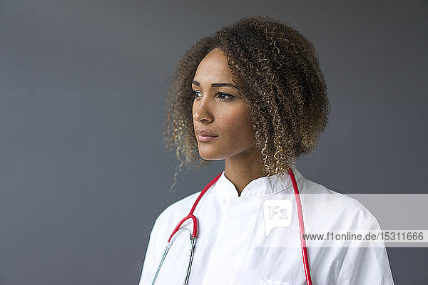 Porträt eines jungen Arztes mit Stethoskop vor grauem Hintergrund