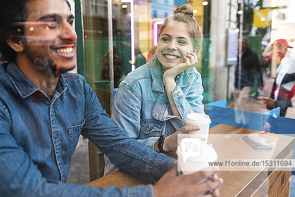 Porträt einer lächelnden jungen Frau in einem Café  die einen jungen Mann anschaut