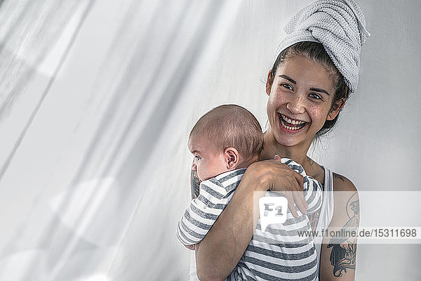 Glücklich tätowierte junge Frau hält ihr Baby
