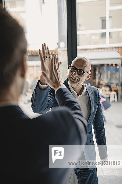 Senior and mid-adult businessman high fiving