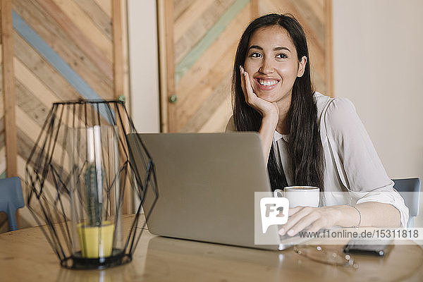 Junge Geschäftsfrau mit Laptop am Tisch in einem Café  die eine Pause macht