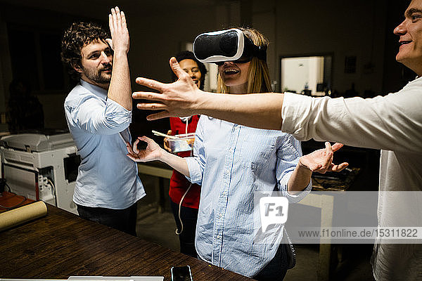 Colleagues with woman wearing VR glasses in office