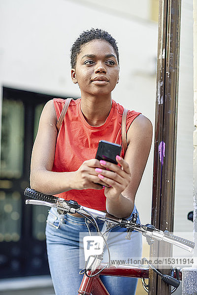 Porträt einer jungen Frau  die sich auf den Lenker eines Fahrrades stützt und in die Ferne schaut