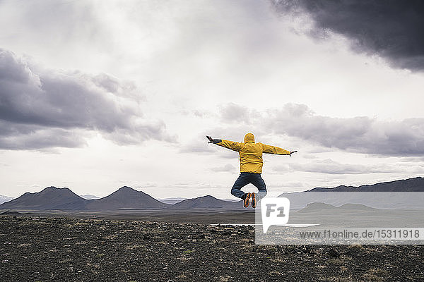 Reifer Mann springt vor Freude an einem Lavastrand in Island