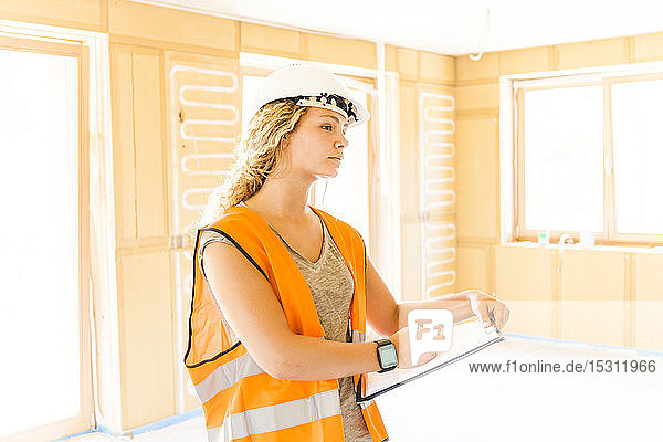 Junge Frau prüft den Bau eines neuen Holzhauses