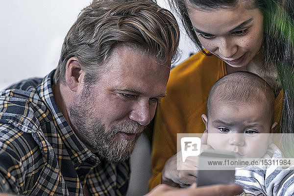 Familie mit Baby benutzt Mobiltelefon