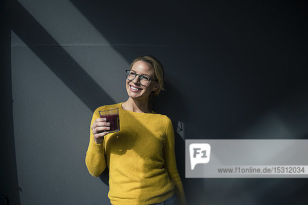 Woman in yellow pullover  holding glass of tea  enjoying the sun