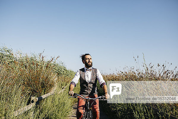 Well dressed man with his bike on a wooden walkway in the countryside after work