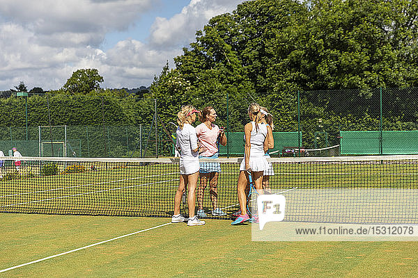 Reife Frauen beenden Tennisspiel auf Rasen
