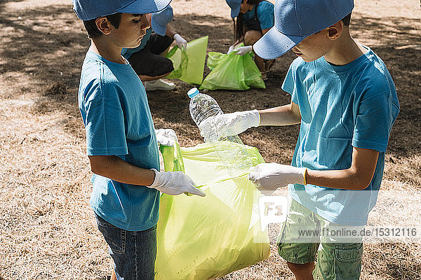 Gruppe ehrenamtlich arbeitender Kinder  die in einem Park Müll sammeln