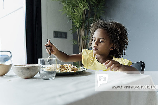 Girl eating pasta at dining table