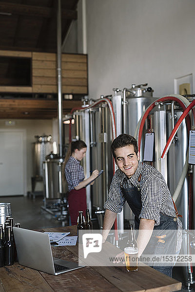 Lächelnder Jungunternehmer bei der Arbeit in einer Brauerei
