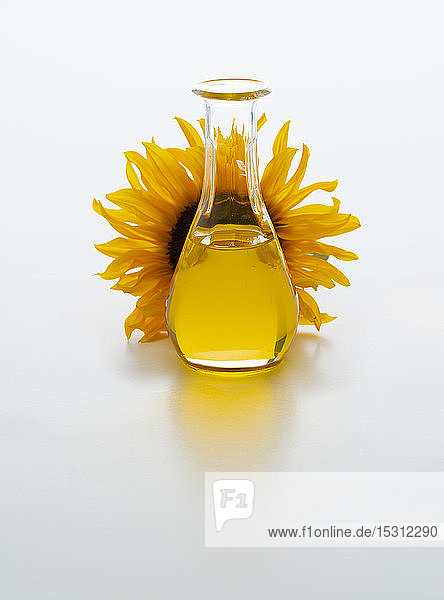Sonnenblumenöl in Karaffe mit Sonnenblumenblüte